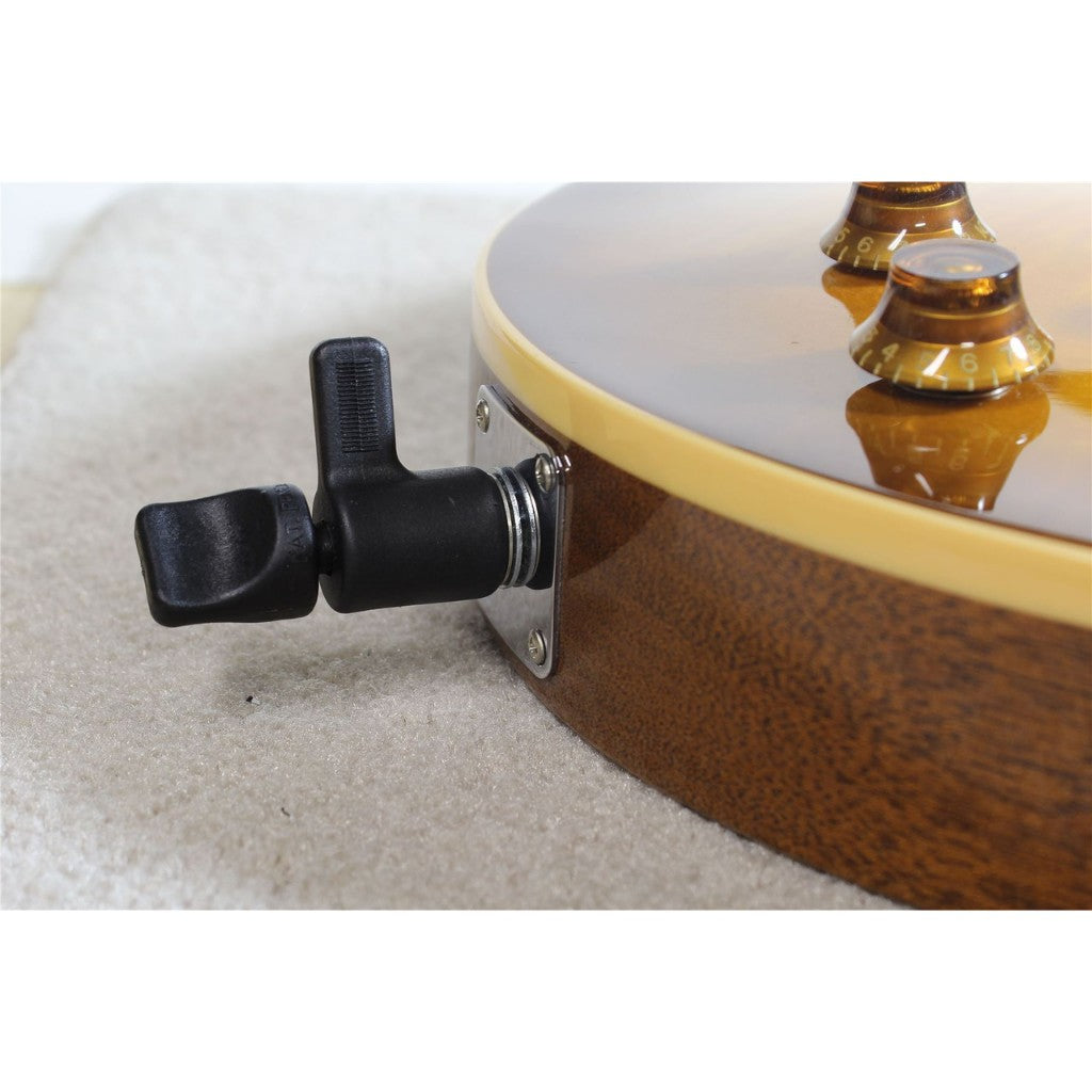 Close-up of a guitar's side showing a black tailpiece tuner on a metal mounting plate, with a brown wood-grain body and gold-toned hardware.
