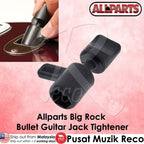 A black Allparts Big Rock Bullet Guitar Jack Tightener shown on a pink background with an inset photo of a hand using the tool on a guitar jack. The Allparts logo is visible at the top right, and text at the bottom identifies the product.