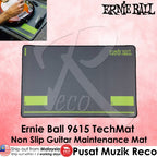 Ernie Ball 9615 TechMat non-slip guitar maintenance mat in dark gray with lime green accents, shown on a pink background with product text and a small inset photo of a hand using it.