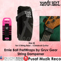 Ernie Ball fret wrap string dampener shown in a product layout with its retail packaging on the left, the main black dampener on the right, and a lifestyle inset photo of a bass guitar neck wearing the dampener on a green headstock. The background is a textured light pink.