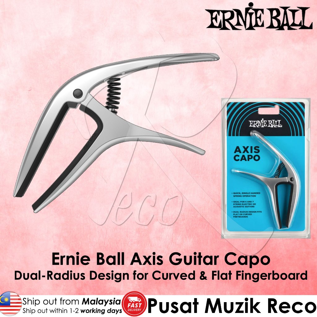 Ernie Ball Axis Guitar Capo in silver metal shown next to its blue and black retail blister packaging on a pink background, with Ernie Ball branding and product text.