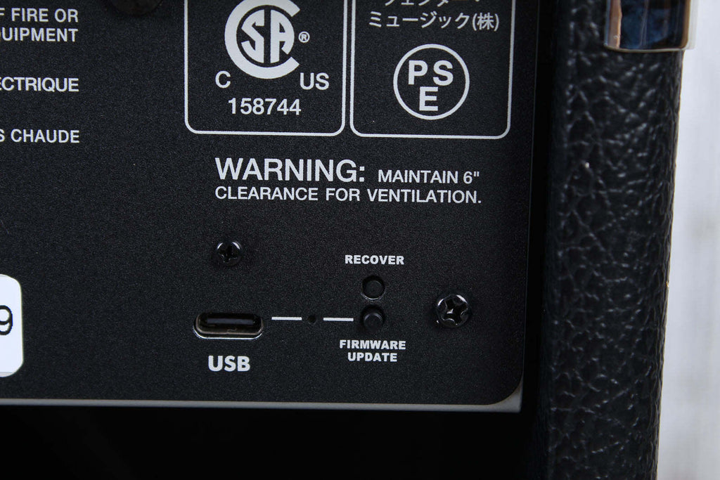 Back panel of a device with warning label, USB port, and other labels on a black background.