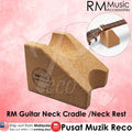 A cork guitar neck cradle shown on a pink background, with a small inset showing part of a guitar neck resting on it. Text includes RM Music Accessories branding and Malay text describing the product.