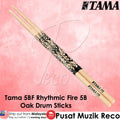 Tama 5BF Rhythmic Fire 5B Oak Drum Sticks on a pink background with Tama logo.